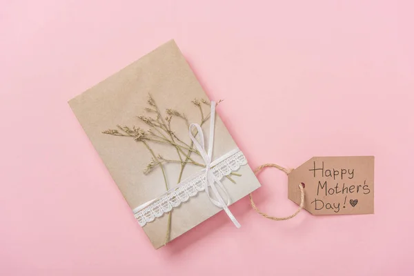 Tarjeta de felicitación del día de las madres decorada con planta seca y cinta de encaje, con texto de felicitación feliz día de las madres sobre fondo rosa - foto de stock