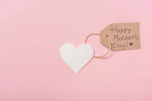 Papel coração e etiqueta de madeira com mães felizes dia saudação texto no fundo rosa — Fotografia de Stock