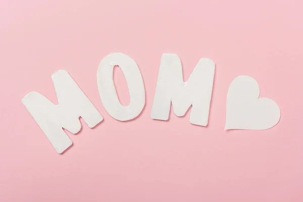 White paper word mom and paper heart on pink background — Stock Photo