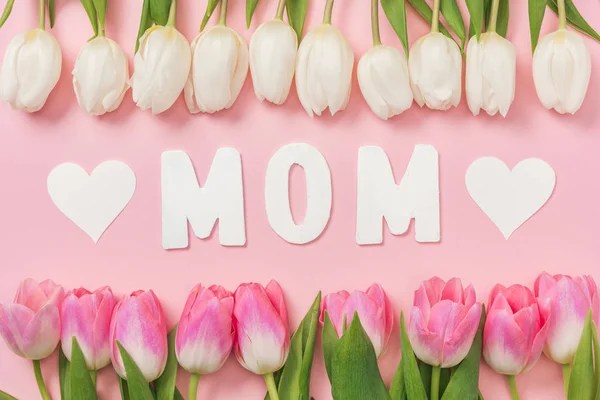 Tulipanes blancos y rosados, palabra de papel mamá y corazones de papel sobre fondo rosa — Stock Photo