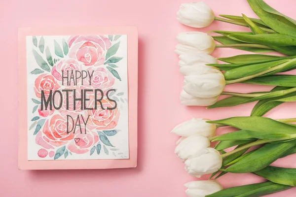 Feliz día de las madres tarjeta de felicitación y tulipanes blancos sobre fondo rosa - foto de stock
