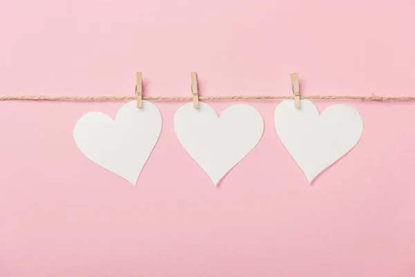 White paper hearts with coarse thread on pink background — Stock Photo