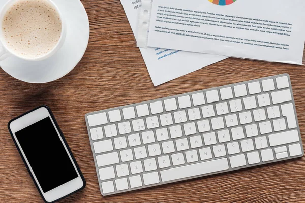 Visão superior do teclado, smartphone com tela em branco e xícara de café no fundo de madeira — Fotografia de Stock