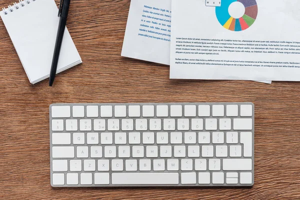 Vista superior do teclado, notebook e documentos sobre fundo de madeira — Fotografia de Stock