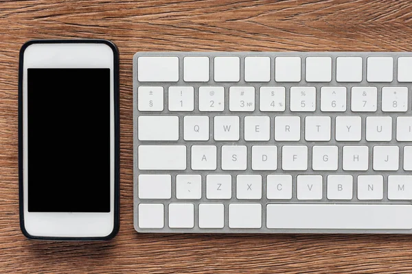 Top view of smartphone with blank screen and keyboard on wooden background — Stock Photo