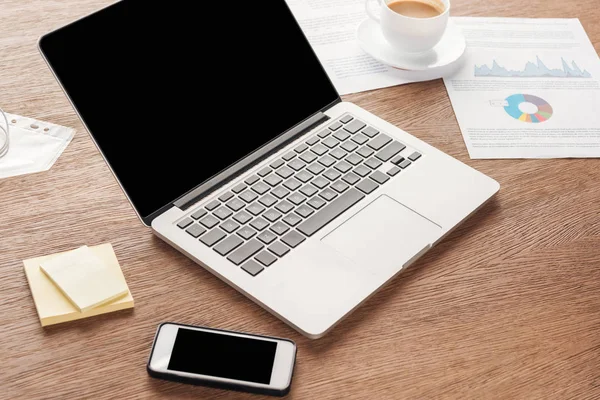 Photo d'un ordinateur portable et d'un smartphone avec écran blanc sur le lieu de travail — Photo de stock