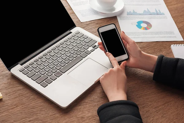 Vista ritagliata di ragazza che tiene smartphone con schermo vuoto sul posto di lavoro — Foto stock