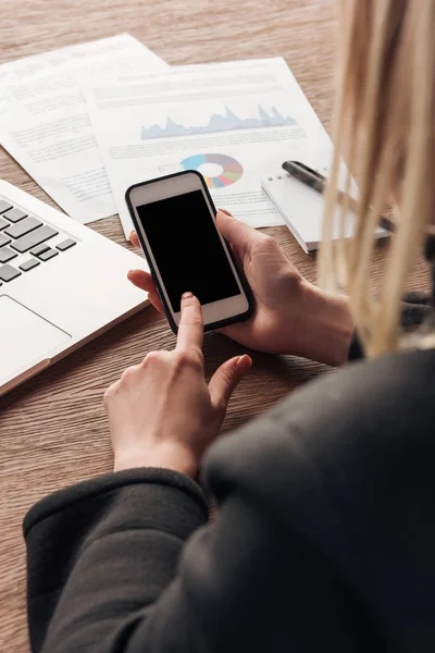 Vista parcial de la mujer sosteniendo el teléfono inteligente con pantalla en blanco - foto de stock