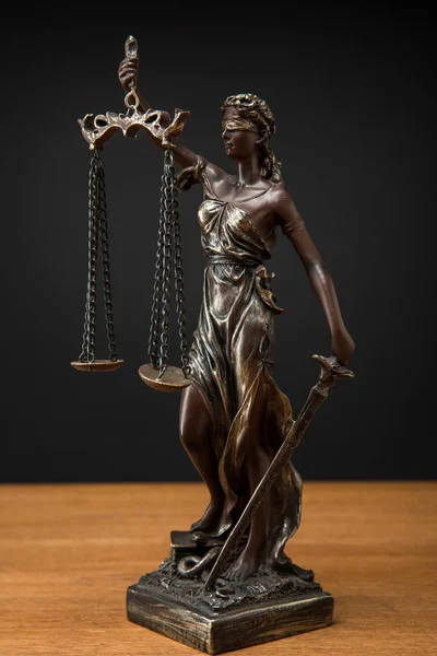 Bronze statuette with scales of justice on wooden table isolated on black — Stock Photo