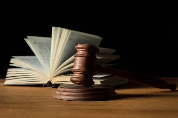 Foyer sélectif de livre ouvert et marteau sur table en bois isolé sur noir — Photo de stock