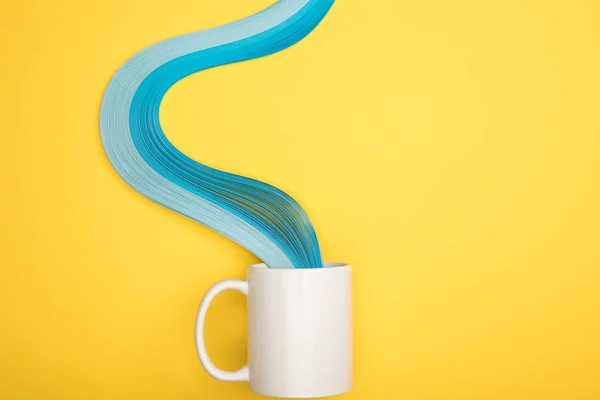 Вид зверху на білу чашку і сині вигнуті лінії на жовтому фоні — стокове фото