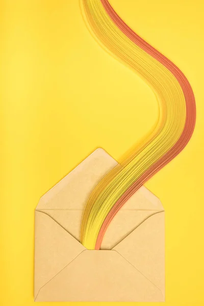 Вид сверху на открытый желтый конверт с радугой на желтом фоне — стоковое фото