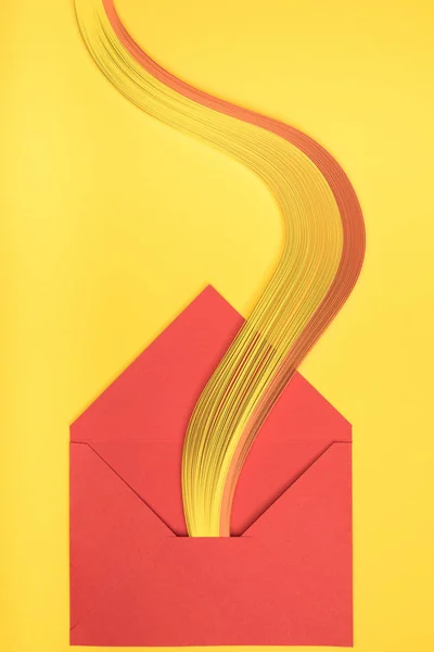 Top view of open red envelope with rainbow on yellow background — Stock Photo