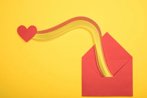 Top view of open red envelope with rainbow and heart sign on yellow background — Stock Photo