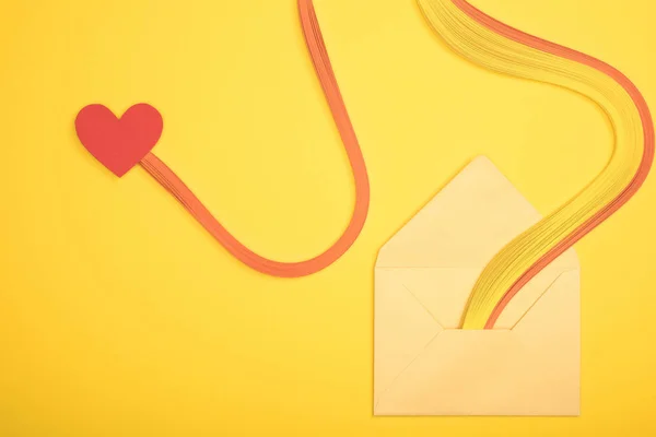 Top view of open envelope with rainbow and heart sign on yellow background — Stock Photo