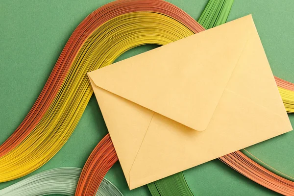 Top view of multicolored abstract lines on green background with yellow envelope — Stock Photo