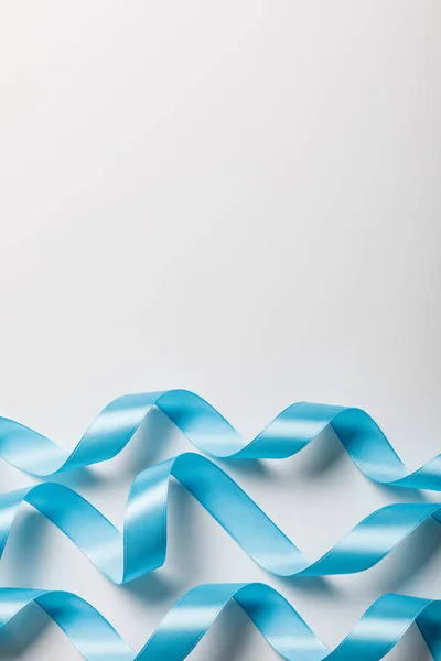 Top view of blue wavy satin ribbons on grey background with copy space — Stock Photo