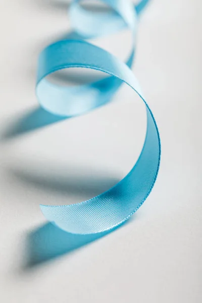Закрытие изогнутой голубой атласной ленты на сером фоне — стоковое фото