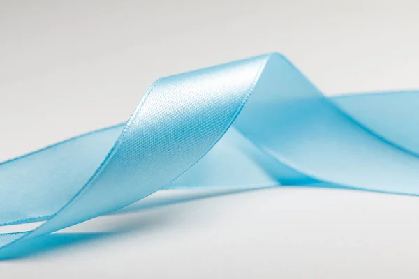 Close up of curved blue silk ribbon on grey background — Stock Photo