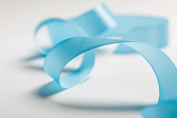 Close up of wavy blue satin ribbon on grey background — Stock Photo