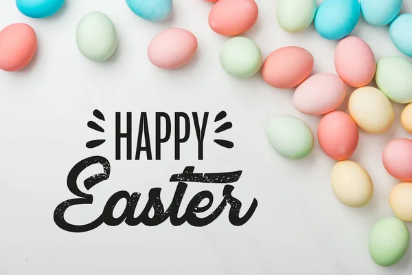 Top view of multicolored chicken eggs on grey background with happy Easter black lettering — Stock Photo