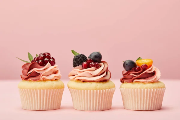 Süße Cupcakes mit Früchten und Beeren auf rosa Oberfläche — Stockfoto