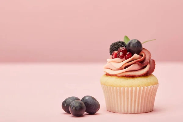 Sweet cupcake with cream and grapes on pink surface — Stock Photo