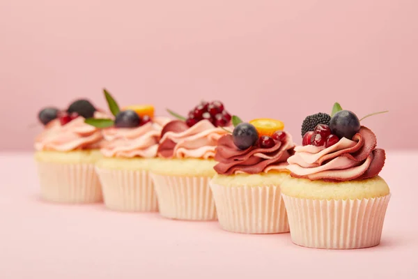 Солодкі кекси з фруктами та ягодами на рожевій поверхні — стокове фото