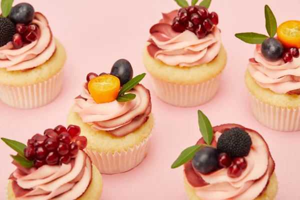 Солодкі кекси з фруктами та ягодами на рожевій поверхні — стокове фото
