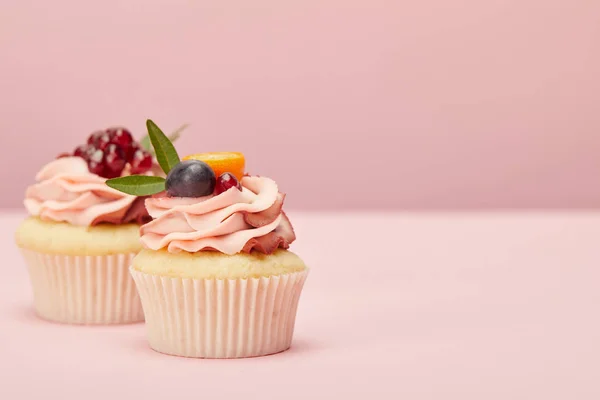 Süße Cupcakes mit Früchten und Beeren auf rosa Oberfläche — Stockfoto