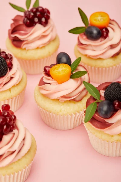 Sweet cupcakes with fruits and berries on pink surface — Stock Photo