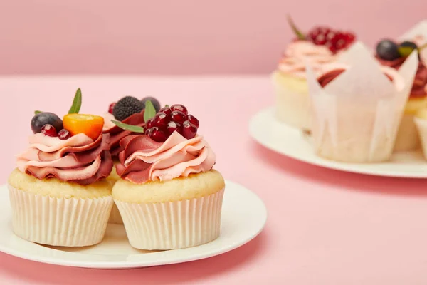 Two plates with sweet cakes on pink surface — Stock Photo