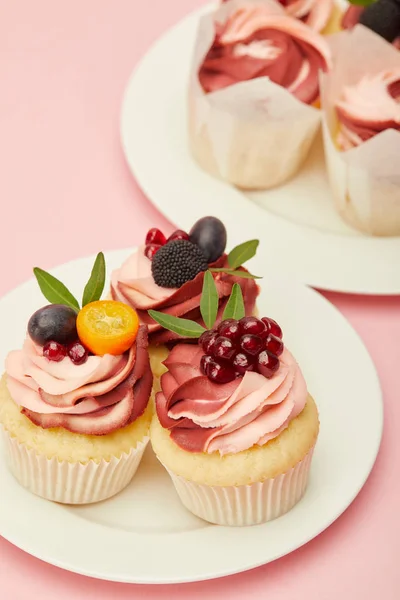 Two plates with sweet cakes on pink surface — Stock Photo