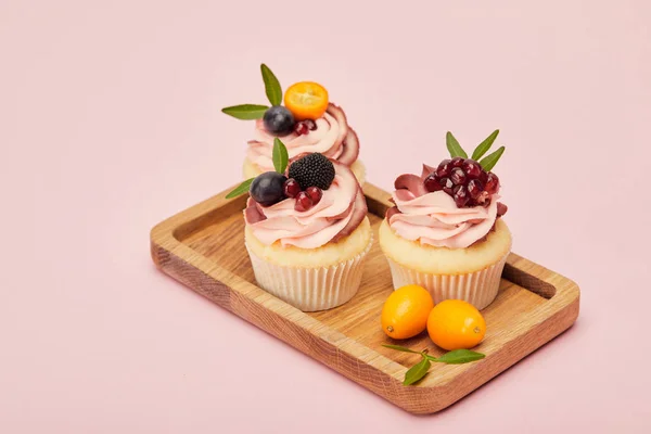 Sweet cupcakes with berries and fruits isolated on pink — Stock Photo