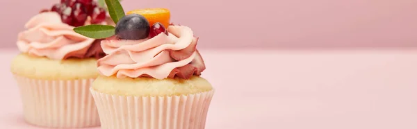 Plano panorámico de pastelitos dulces con bayas y frutas en la superficie rosa - foto de stock
