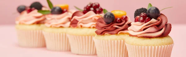 Panoramaaufnahme von süßen Cupcakes mit Beeren und Früchten auf rosa Oberfläche — Stockfoto