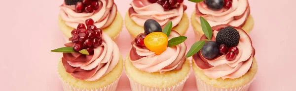 Tiro panorâmico de cupcakes doces com bagas e frutas na superfície rosa — Fotografia de Stock