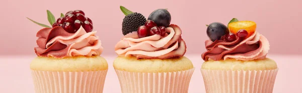 Plano panorámico de pastelitos dulces con bayas y frutas en la superficie rosa - foto de stock