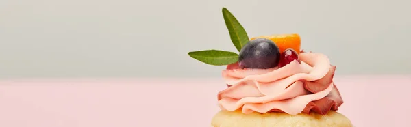 Panoramic shot of cupcake with grape, kumquat and garnet on grey and pink — Stock Photo