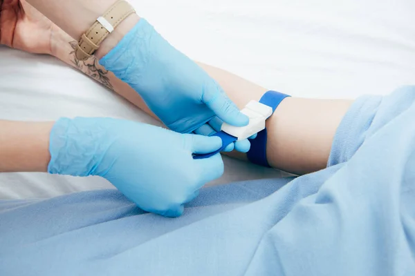 Visão parcial do médico usando torniquete para análise de sangue no hospital — Fotografia de Stock