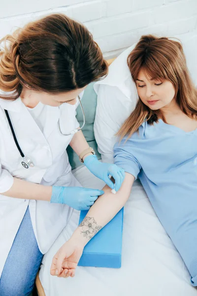 Arzt in Latexhandschuhen bereitet Spender auf Blutspende vor — Stockfoto