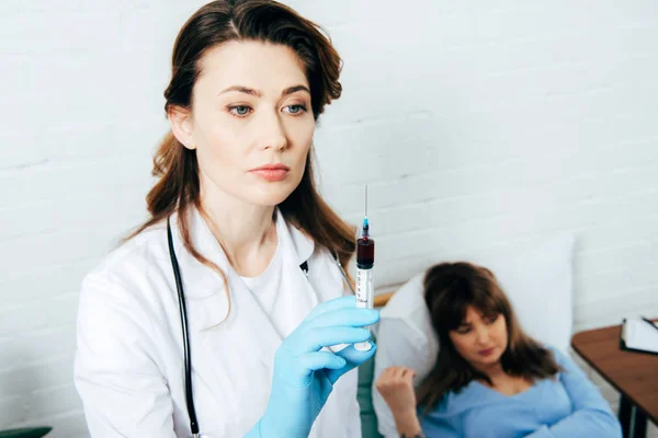 Spender liegt auf Bett und Arzt hält Spritze mit Blutprobe — Stockfoto