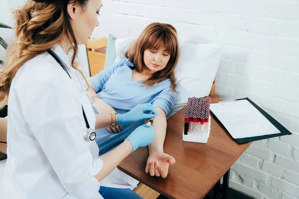 Vista recortada de donante y médico con jeringa obtención de muestra de sangre - foto de stock