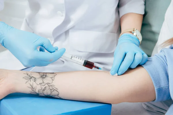 Vista recortada de donante y médico con jeringa obtención de muestra de sangre - foto de stock