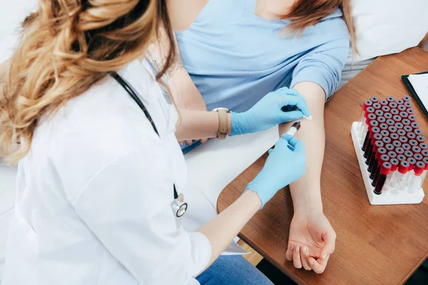 Vista recortada de donante y médico con jeringa obtención de muestra de sangre - foto de stock