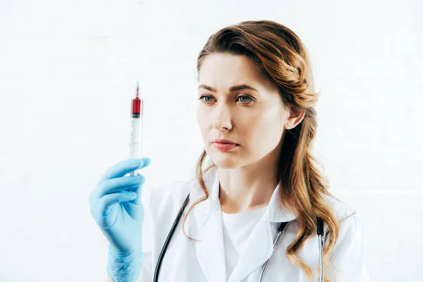 Médico em seringa de retenção de casaco branco com amostra de sangue em branco — Fotografia de Stock