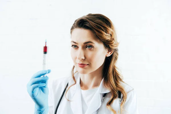 Médico em seringa de retenção de casaco branco com amostra de sangue em branco — Fotografia de Stock