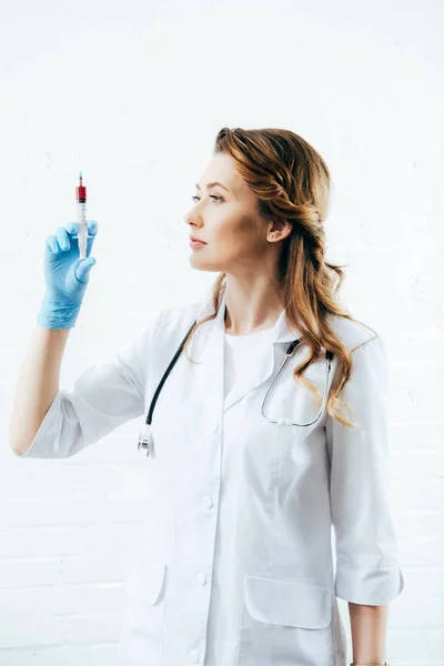 Arzt im weißen Kittel hält Spritze mit Blutprobe auf weiß — Stockfoto