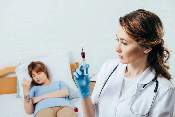 Spender auf dem Bett und Arzt hält Spritze mit Blutprobe — Stockfoto