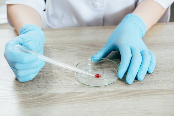 Cropped view of doctor in latex gloves holding pipette with blood sample — Stock Photo